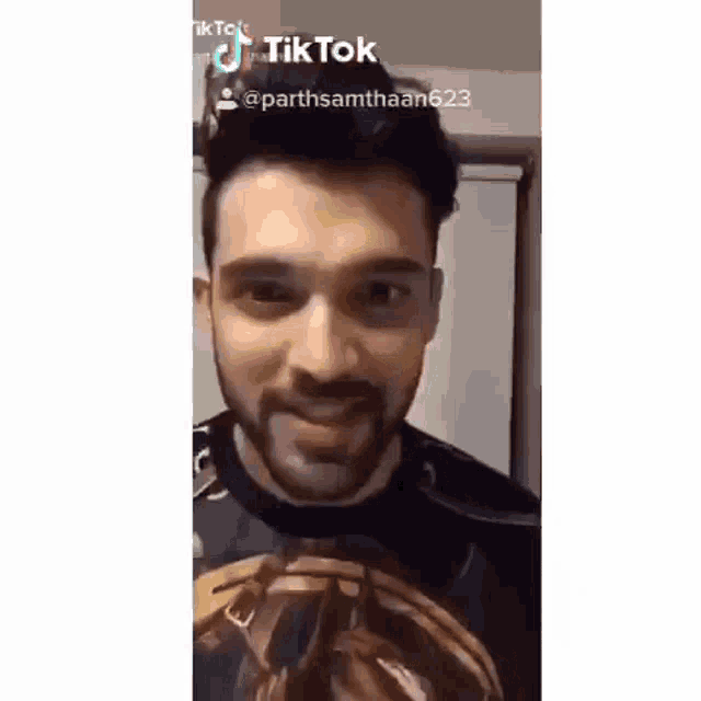 a man with a beard is smiling and looking at the camera while wearing a black shirt .