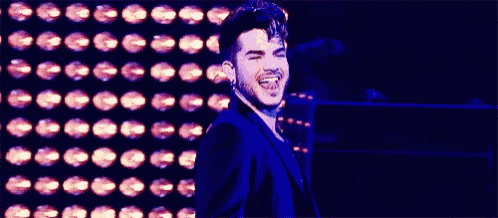 a man in a suit and tie is smiling in front of a wall of lights .