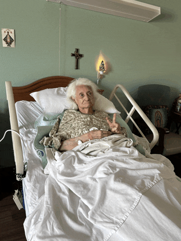 an elderly woman in a hospital bed giving a thumbs up sign