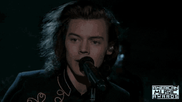 a man singing into a microphone with the words american music awards above him