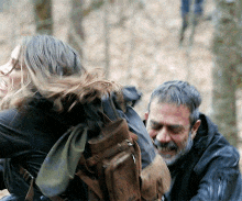 a man with a beard is holding a woman in a forest