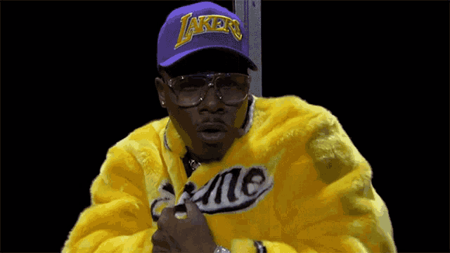 a man wearing a purple lakers hat and a yellow jacket