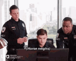 a group of police officers are standing around a man sitting in front of a computer screen ..