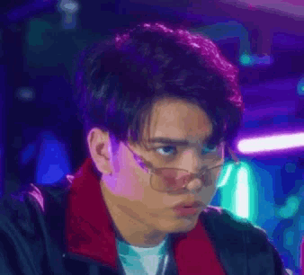 a young man wearing glasses and a red scarf looks at the camera .