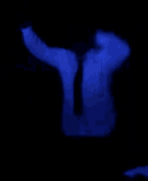 a man in a white shirt and tie is dancing in the dark .