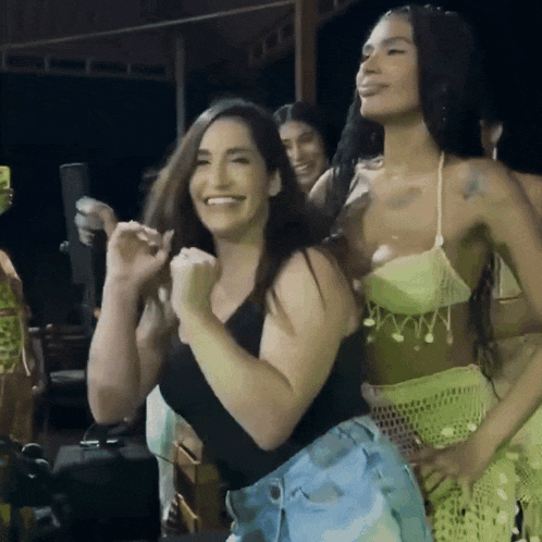 a group of women are dancing and smiling in a dark room