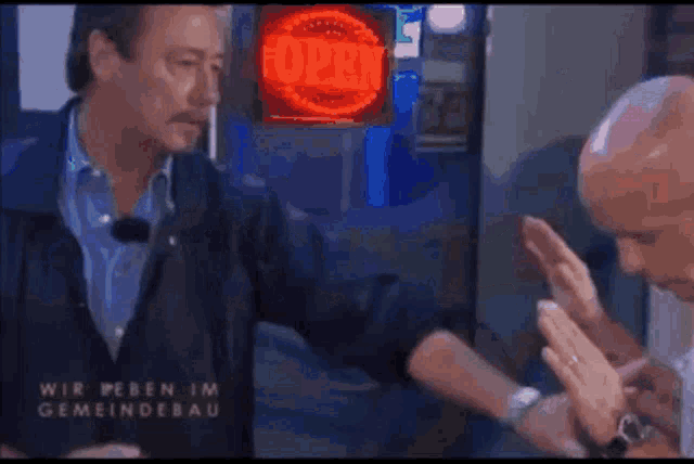 two men are dancing in a dark room with the words wir leben im gemeindebau written on the bottom