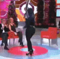 a woman is dancing on a pole in front of a group of people