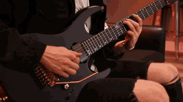 a man is playing an electric guitar with a sticker on the neck that says ' ec '