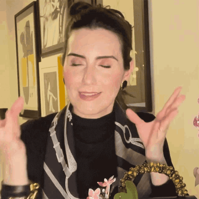 a woman wearing a scarf and a black turtleneck is smiling