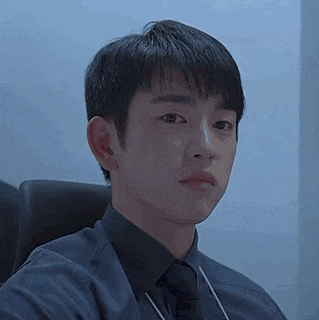 a young man in a suit and tie is sitting in a chair and looking at the camera .