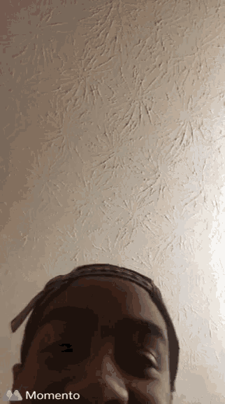 a man 's face is shown in front of a white wall and the word momento is on the bottom