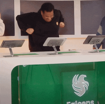 a man stands at a desk with a falcons logo on it