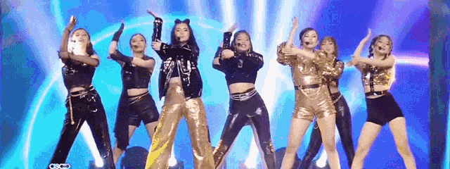 a group of women are dancing on a stage in front of a blue background