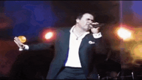 a man in a suit singing into a microphone on a stage