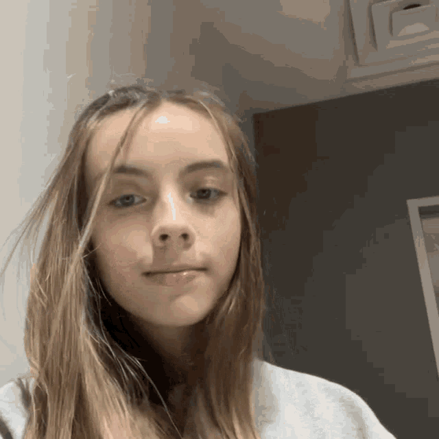 a young girl with long hair looks at the camera with a serious look on her face