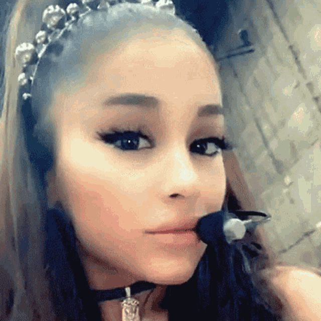 ariana grande is wearing a choker and a headband with pearls on it .
