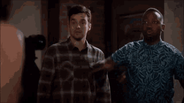 two men are standing next to each other in a room and one of them is pointing .