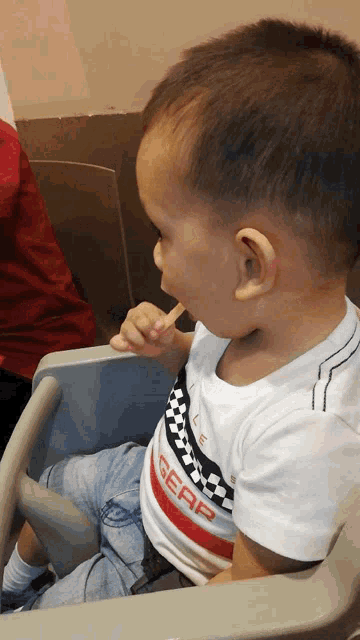 a little boy wearing a shirt that says gear
