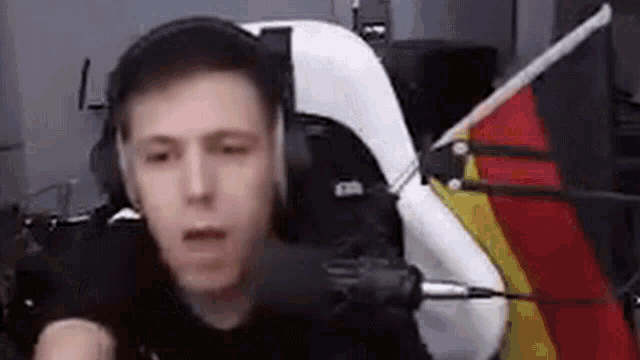a man wearing headphones is sitting in front of a microphone in a room .