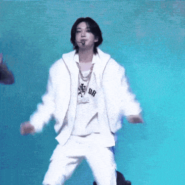 a man in a white jacket and white pants is dancing on a blue background