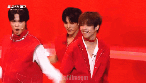 a group of young men in red jackets are dancing on a stage