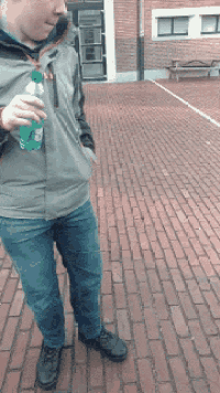 a man is holding a bottle of sprite on a brick sidewalk