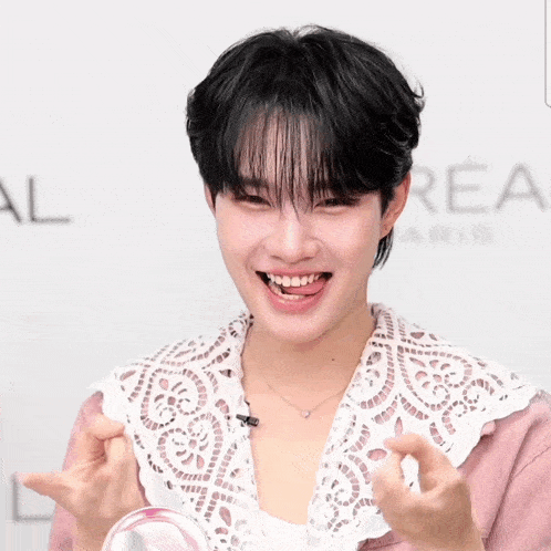 a young man wearing a pink shirt and a white lace collar is smiling