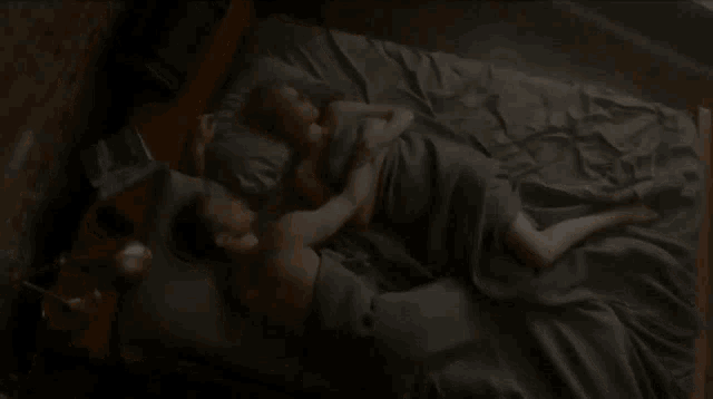 a man and a woman are laying on a bed with a book on the nightstand that says ' a woman ' on it