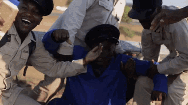 a man in a blue shirt is being held by a group of men
