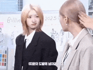 two women in suits are standing next to each other in front of a whiteboard with the year 2025 written on it .