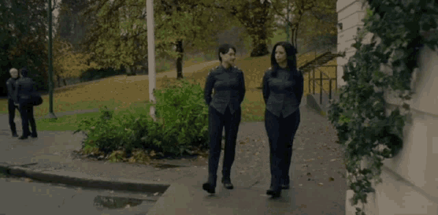 two women are walking down a sidewalk next to each other