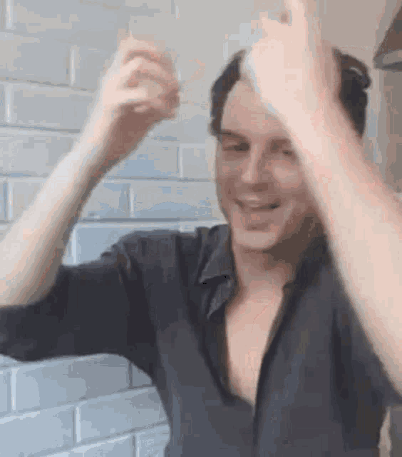 a man in a black shirt is holding a glass in his hand and making a funny face .