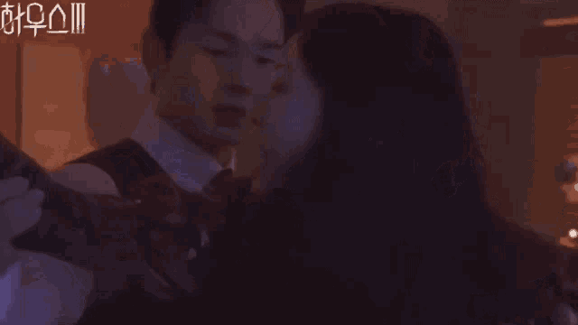 a man in a suit is hugging a woman in a dark room with chinese writing on the bottom