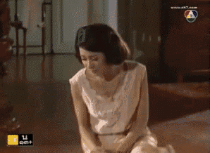 a woman in a white dress is kneeling down on the floor in front of a tv screen that says ek7.com