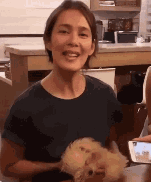 a woman is sitting at a table holding a small dog .