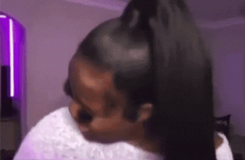 a woman is holding her hair in a ponytail while wearing a white shirt .