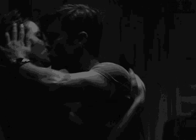 a couple of men are kissing in a dark room .