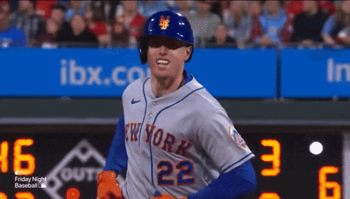 a baseball player for the new york mets is standing in front of the scoreboard