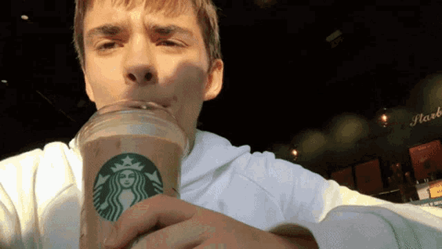 a man is drinking from a starbucks cup with a woman on it