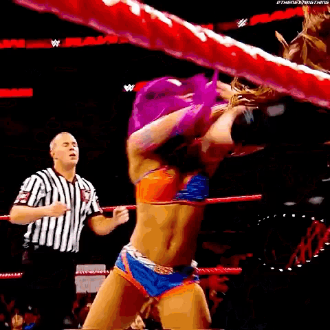 a woman in a bikini is wrestling in a ring with a referee watching .