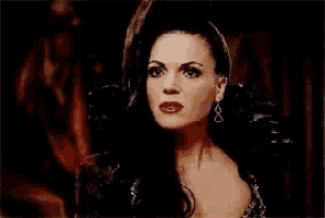 a woman with long black hair and red lipstick is wearing earrings and a crown .