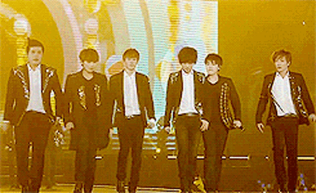 a group of young men in suits are walking on a stage .