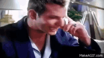 a man in a suit is crying while holding a tissue to his face .