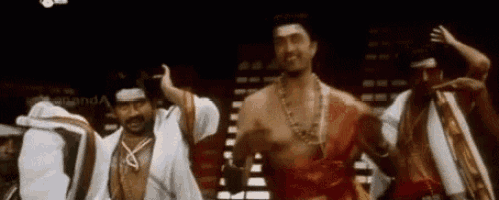 a group of men are dancing together on a stage in a dark room .