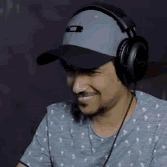 a man wearing headphones and a hat drinks from a glass