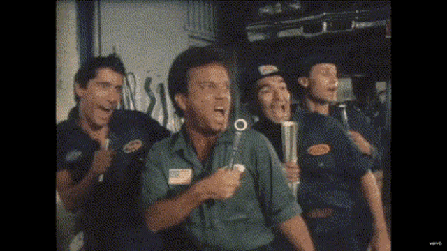 a group of men are standing next to each other in a room holding bottles .