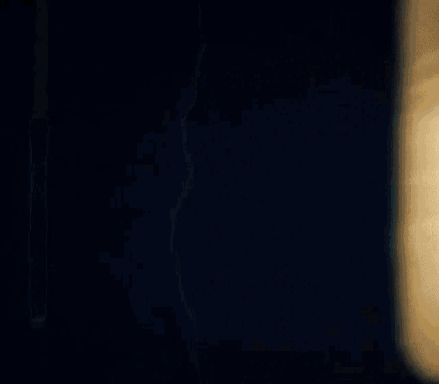 a man is standing in a dark room holding a piece of paper in his hands .