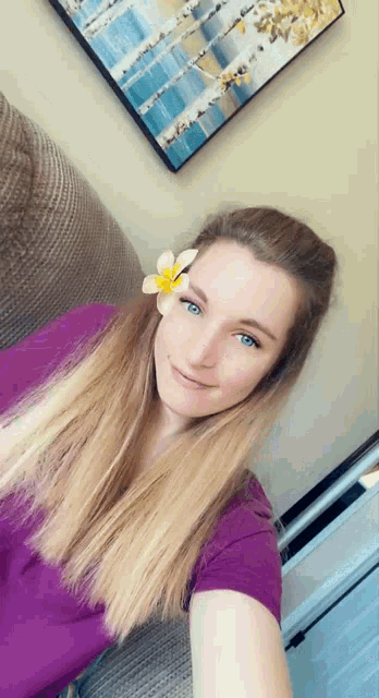 a woman in a purple shirt has a flower in her hair .