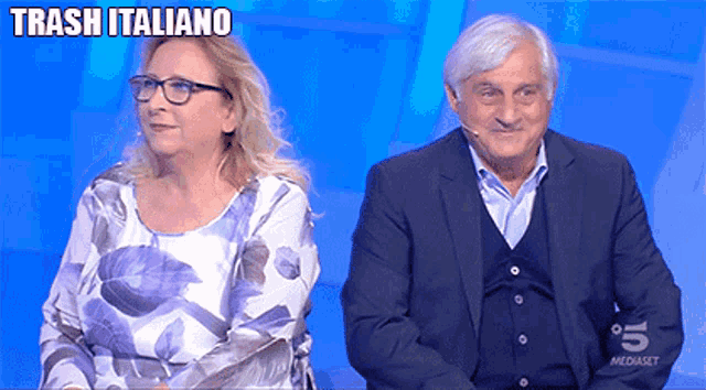 a man and a woman sitting next to each other with trash italiano written on the bottom